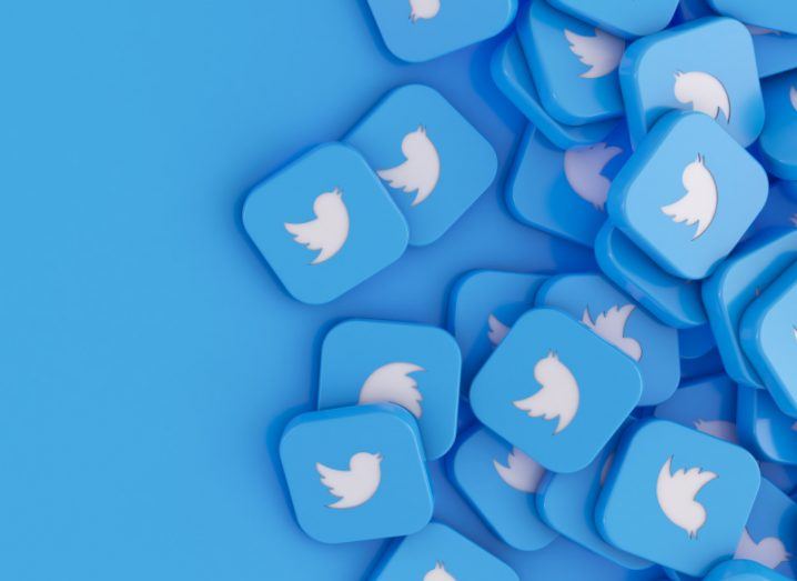 Multiple blue squares with the Twitter logo on them, in a blue background.