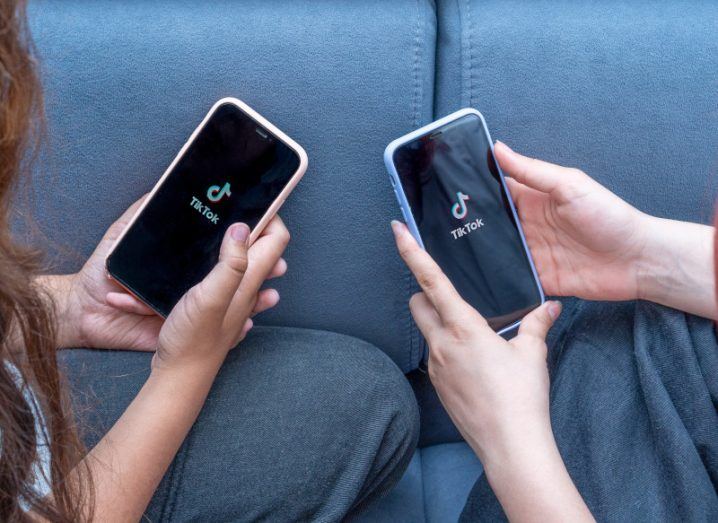 Two teenagers holding smartphones with the TikTok logo on both screens.