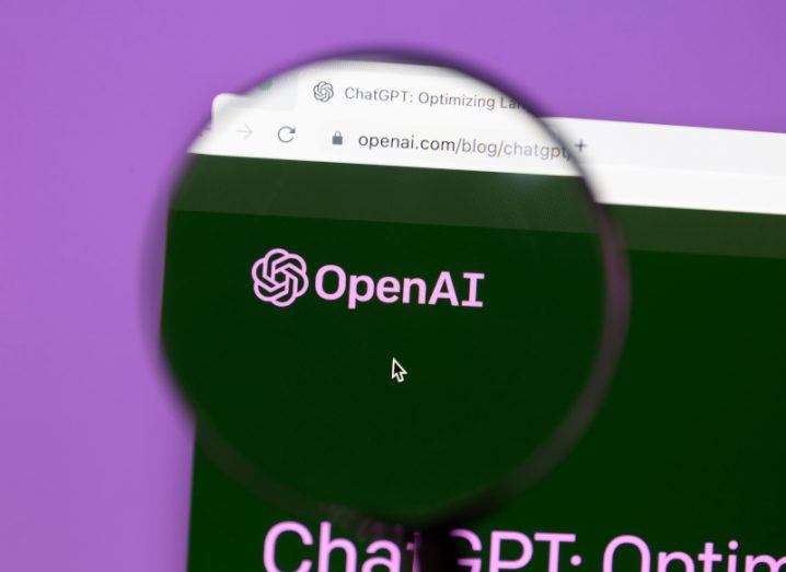 The OpenAI logo on a screen with a magnifying glass over it.