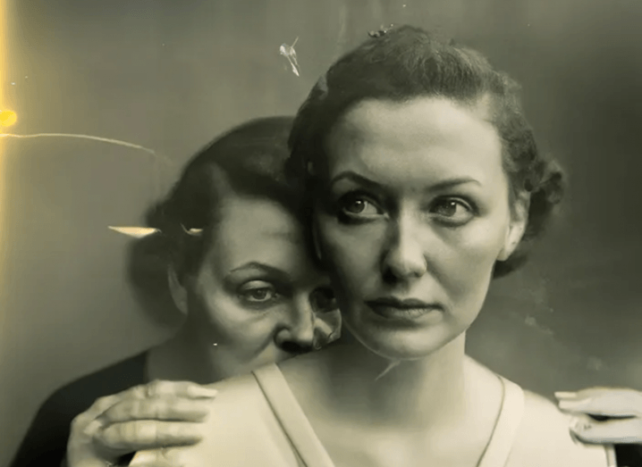 A black-and-white image made by AI of a woman looking into the distance while another woman stands behind her and holds onto her shoulders.