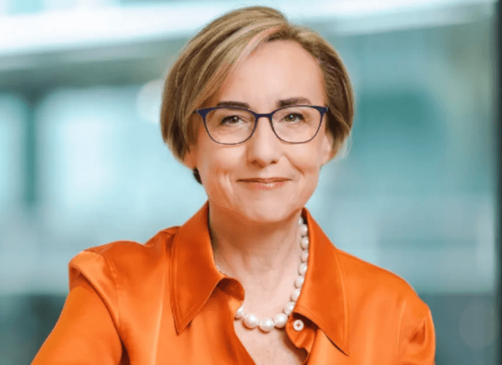 Headshot of a woman wearing an orange shirt with a blurred office background. She is Margherita Della Valle of Vodafone.