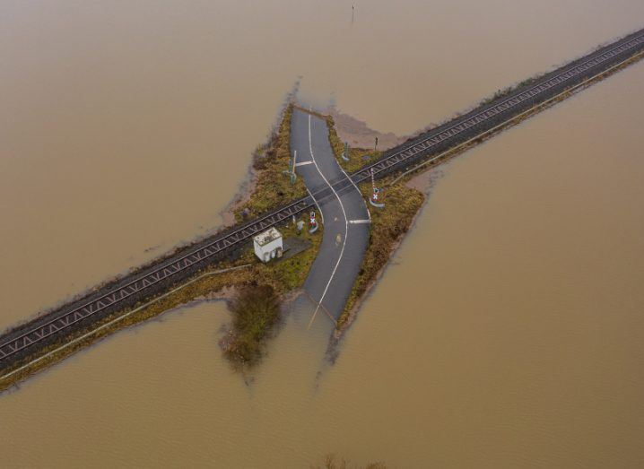 An aerial view of a flood almost covering a road and railway track.
