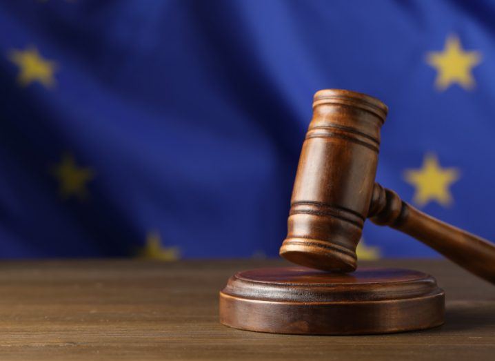 A gavel on a wooden table with the EU flag in the background.