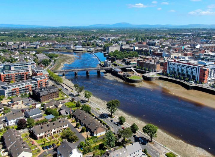 An aerial view of Limerick city, with a river flowing through the centre of the image and multiple buildings on either side.