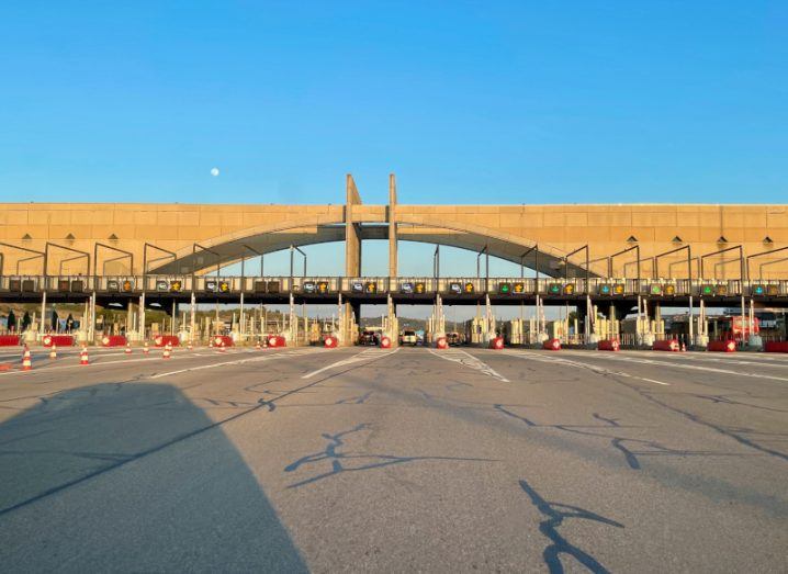 A toll booth on a large road, with a blue sky in the background.