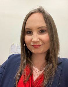 A selfie of Nell Watson. She has brown hair and is wearing a dark blue suit jacket and a red blouse.