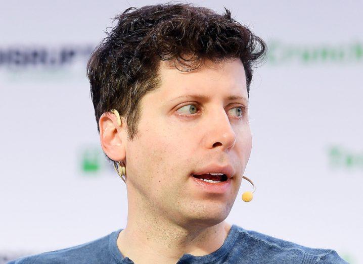 Headshot of Sam Altman wearing a mic and talking from a stage.