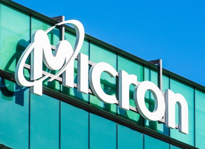 Micron logo in white on a glass building with the blue sky above.