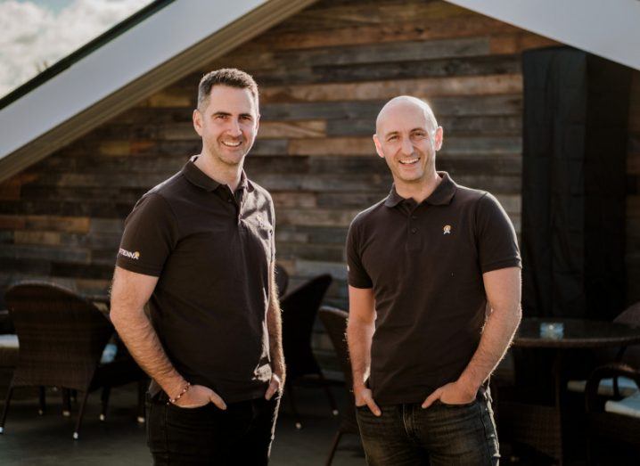 Two men who co-founded Sitenna stand next to each other with hands in pockets.