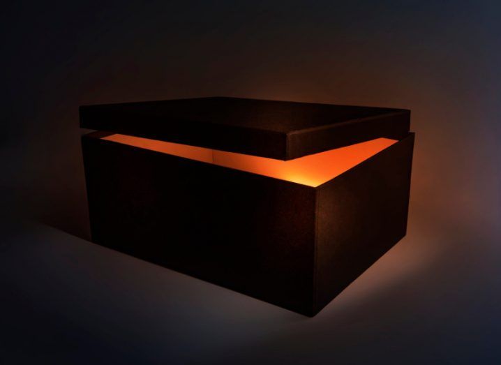 A black rectangular box with the lid slightly open revealing an orange light against a dark background.