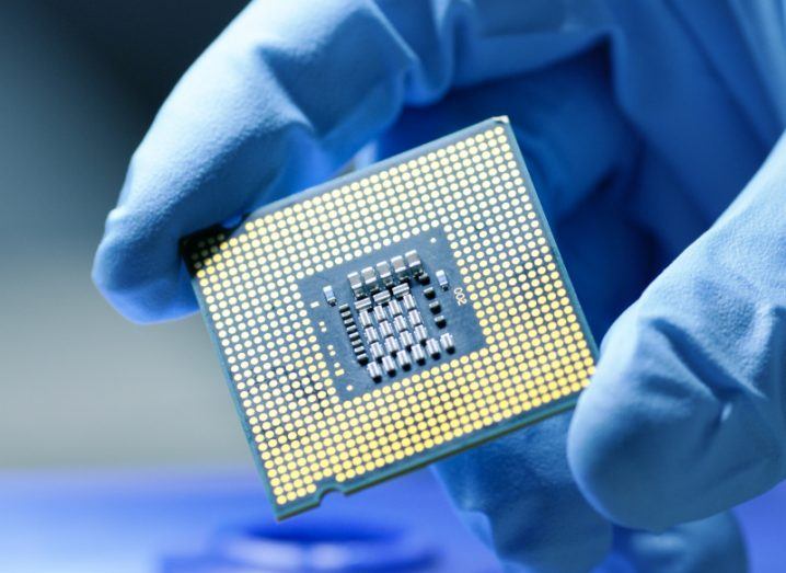 A person wearing a surgical glove holds a microchip close to the camera.