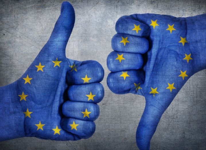 Two hands painted to look like the EU flag with the thumb of one hand pointing up and the thumb of the other hand pointing down.