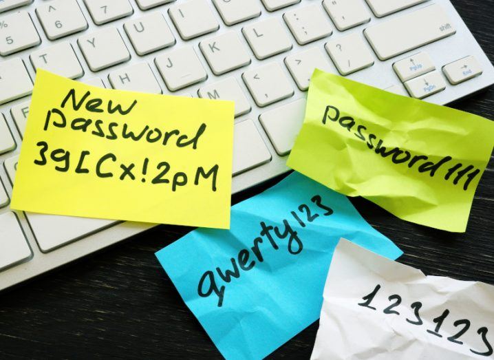 Image of sticky notes with passwords written on them and the paper is slightly crumpled and sitting on a computer keyboard on a desk.