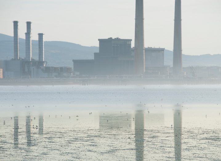 An image of water with the Poolbeg station in the background in Dublin. The image is cloudy and is used to represent emissions and pollution.