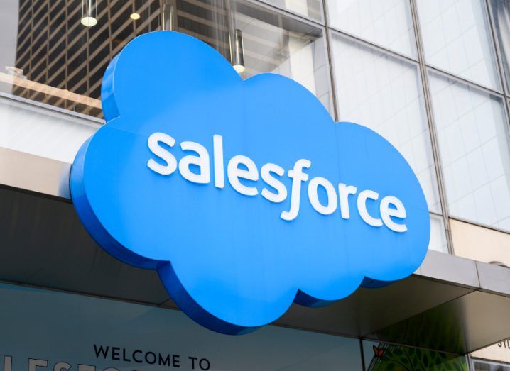 The Salesforce logo in white writing on a blue cloud hanging on the exterior of a building.