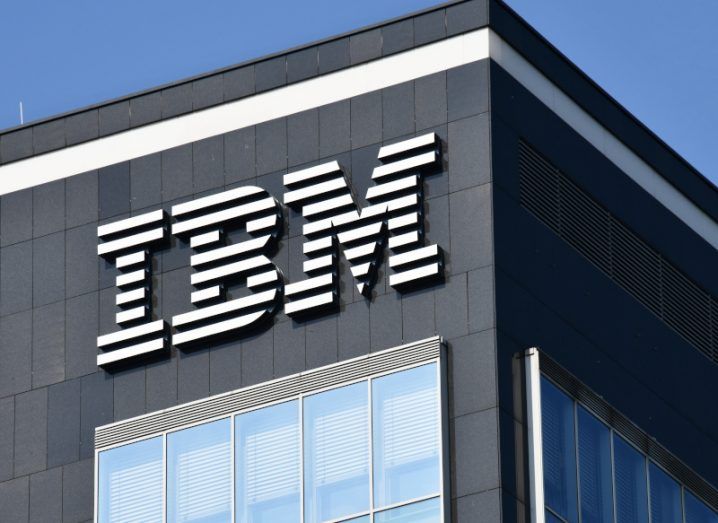 IBM logo on an office building with the sky visible behind it.