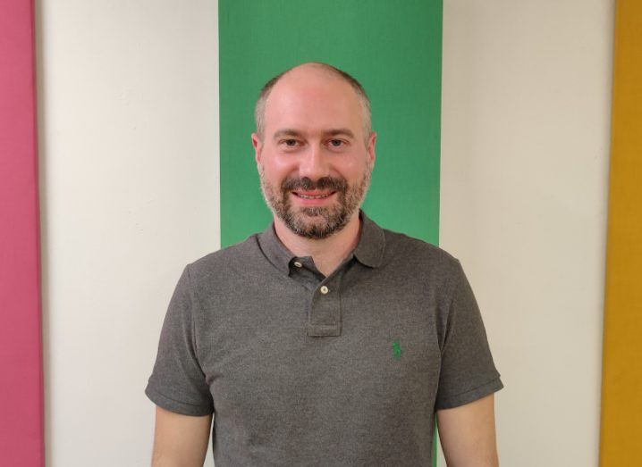 A man in a polo shirt stands against a white and green striped wall. He is David Singleton, CTO of Stripe.