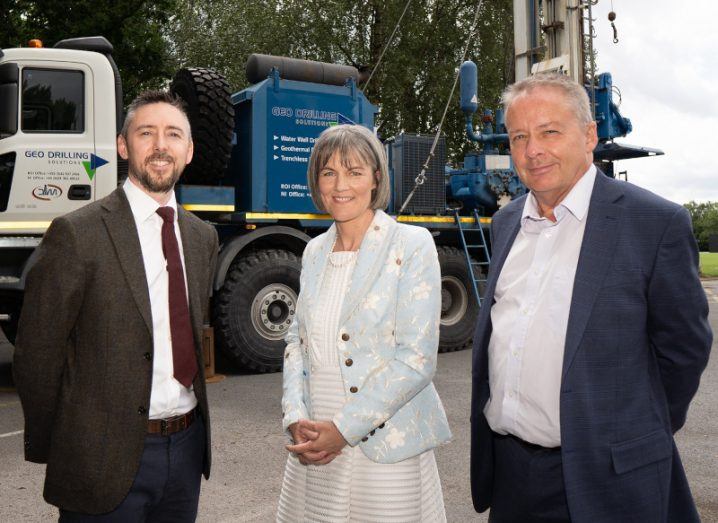 Three people standing in front of a truck outside with trees behind them and the truck.