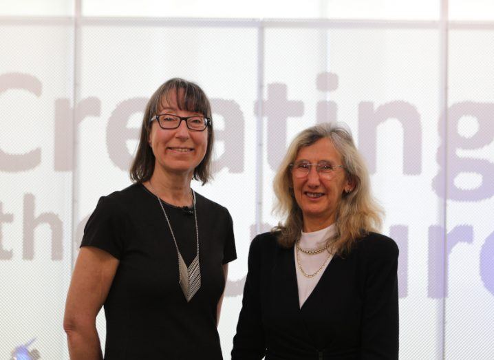 Two women, Ann O’Dea and Prof Orla Hardiman, stand side by side smiling at the camera. The wall behind them says creating the future.