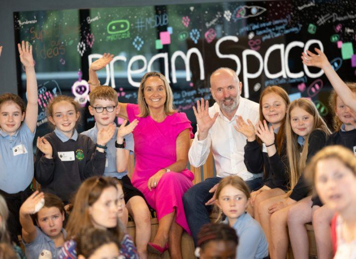 Two adults who work at Microsoft surrounded by many children with the words Dream and Space visible in the background.