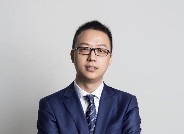 Headshot of incoming Alibaba CEO Eddie Wu wearing a suit with a gray wall behind him.
