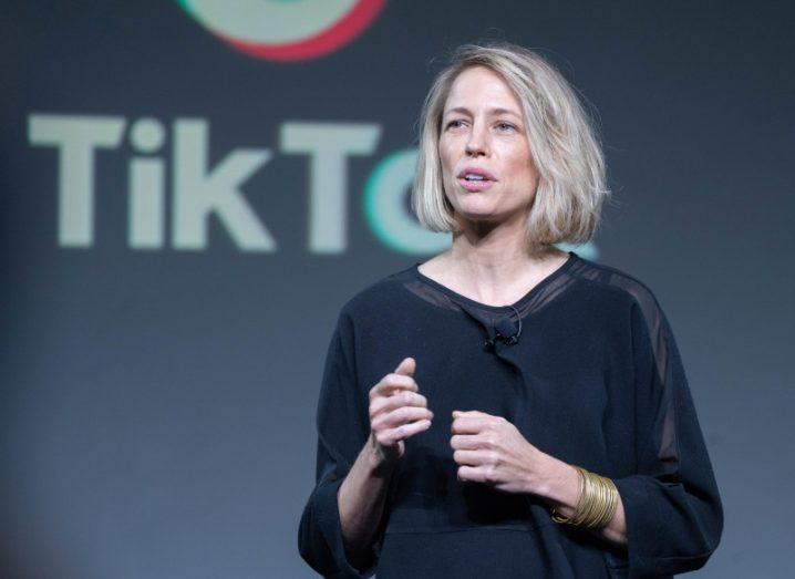 Image of V Pappas, TikTok COO, addressing an audience from stage. There's a TikTok logo behind her.