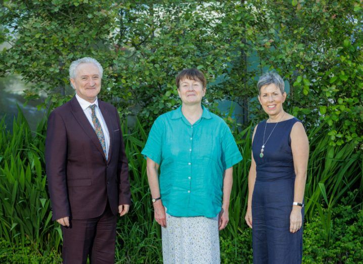 A man and two women stand in a green outdoor space. One of them is Prof Frances Lucy.