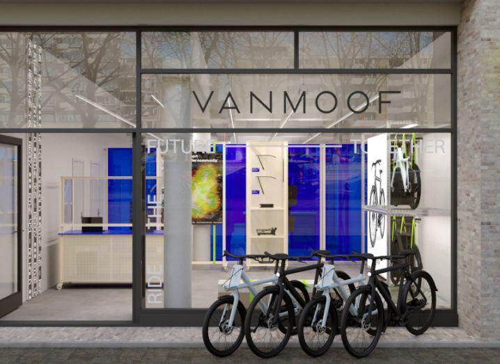 The exterior of a store with the VanMoof name on the window and multiple electric bikes outside.