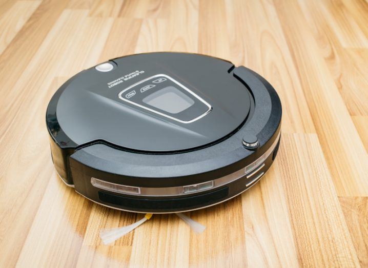 A robot vacuum cleaner on a wooden floor.