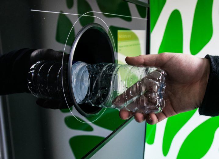 A reverse vending machine, being used by a person to recycle a plastic bottle.