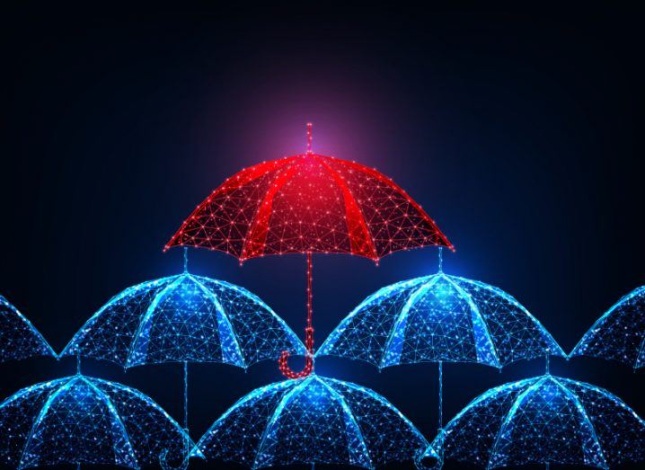 Illustration of a red umbrella above multiple blue umbrellas, in a dark background. Used as a concept for insurance.