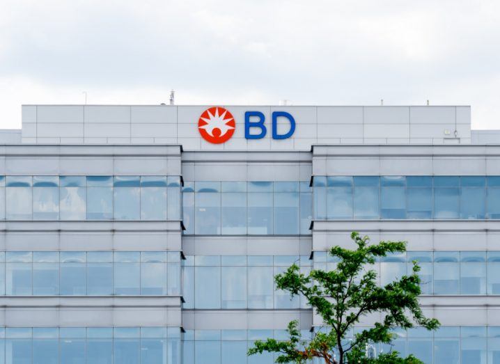 The front of a large office with the BD logo on it and a tree visible in front of it.