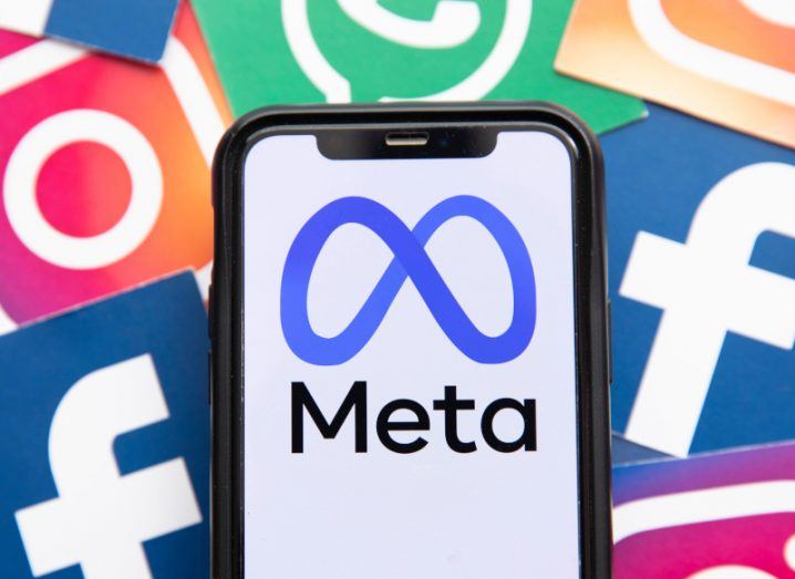 The Meta logo on a smartphone screen, in front of multiple logos of Facebook, Instagram and WhatsApp.