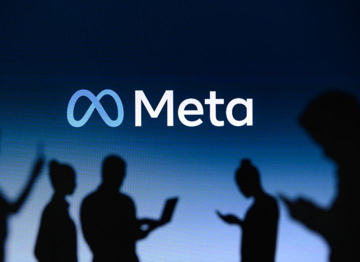 The Meta logo in front of silhouettes of people using media devices.