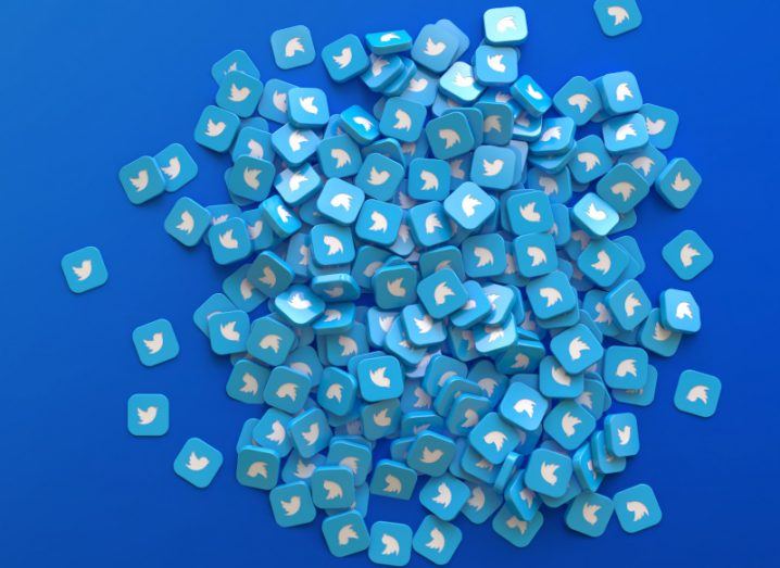 A large pile of blue squares with the Twitter logo on each of them, laying on a dark blue background.