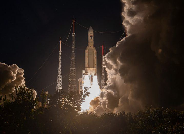 A rocket taking off at night, with flames coming out of its engine and smoke around it. The rocket is the Ariane 5.