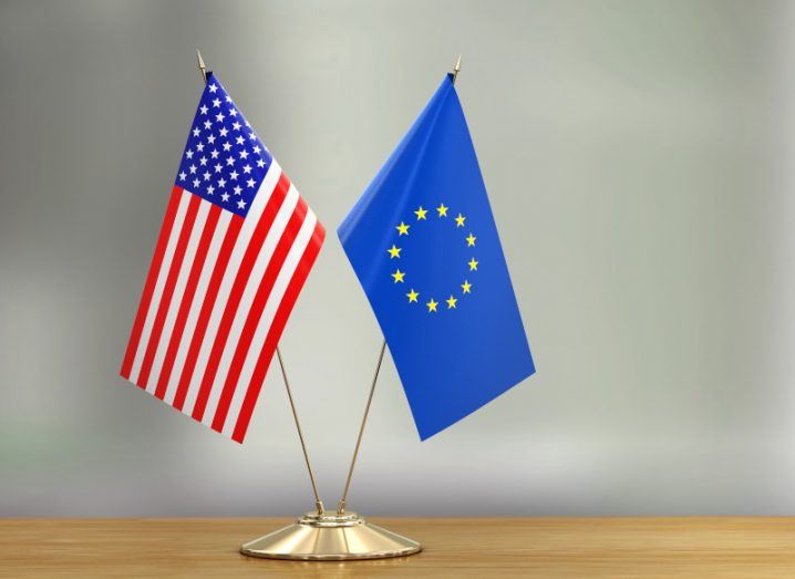 Two small flags – one US and one EU – on a wooden desk, symbolising EU data transfer.