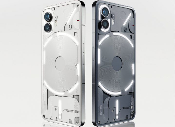 Two smartphones by Nothing, with one coloured black and the other one white. The phones are standing upright in a grey background.