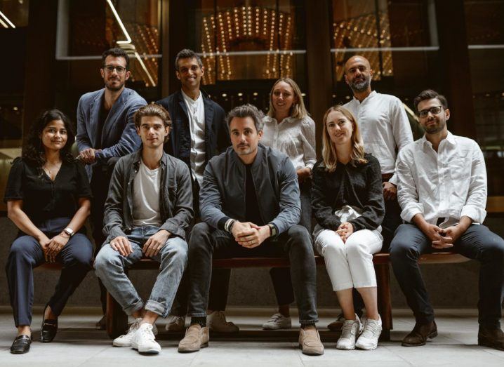 A group of men and women wearing casual clothes standing and seated for a photograph in an indoor space.