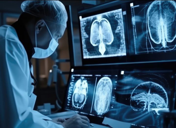 Doctor wearing lab clothes using computers in a dark room. The computers are using generative AI technology to show a human brain on multiple screens and progress health research.