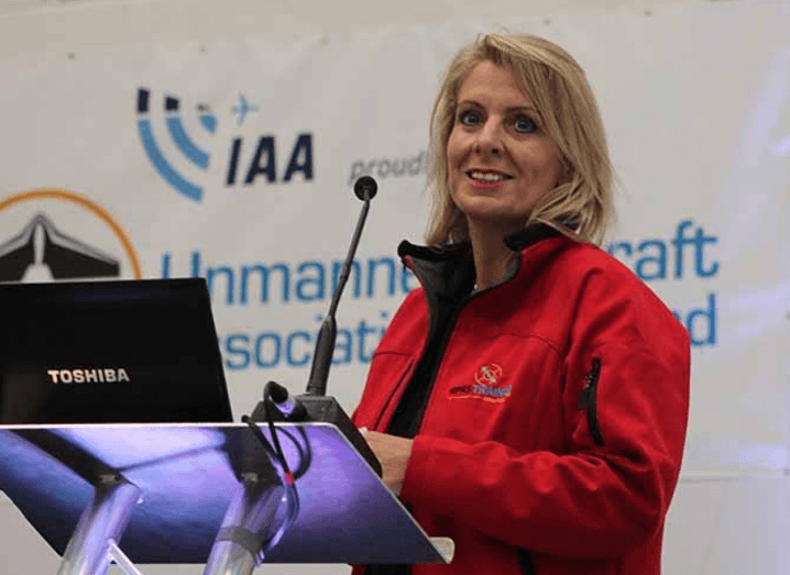 Photo of drone start-up Avtrain CEO Julie Garland speaking from a podium on a stage with the IAA logo on a poster in the backdrop.