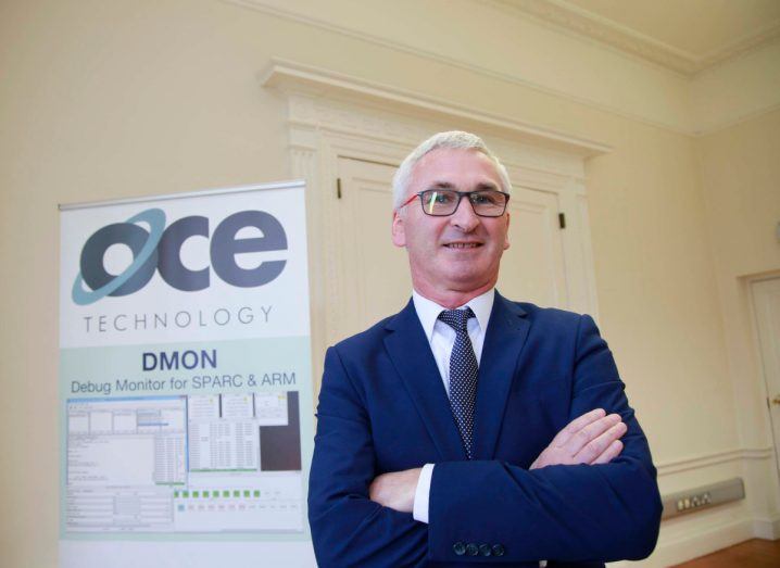 Photo of OCE Technology chief executive Barry Kavanagh wearing a suit with arms folded across his chest. A poster of OCE can be seen in the background.