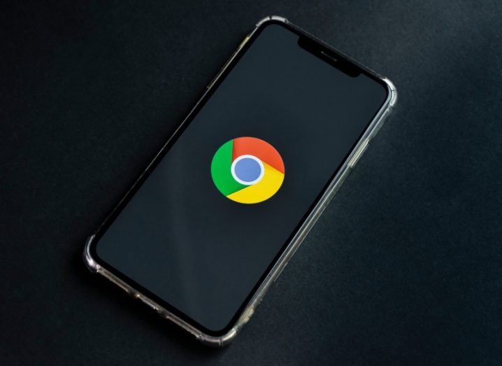 A phone on a black background with the Google Chrome logo displayed on the screen.