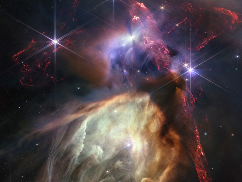 A cloud complex in space, showing different gas clouds of different colours clashing together in space, with multiple stars visible across the image.