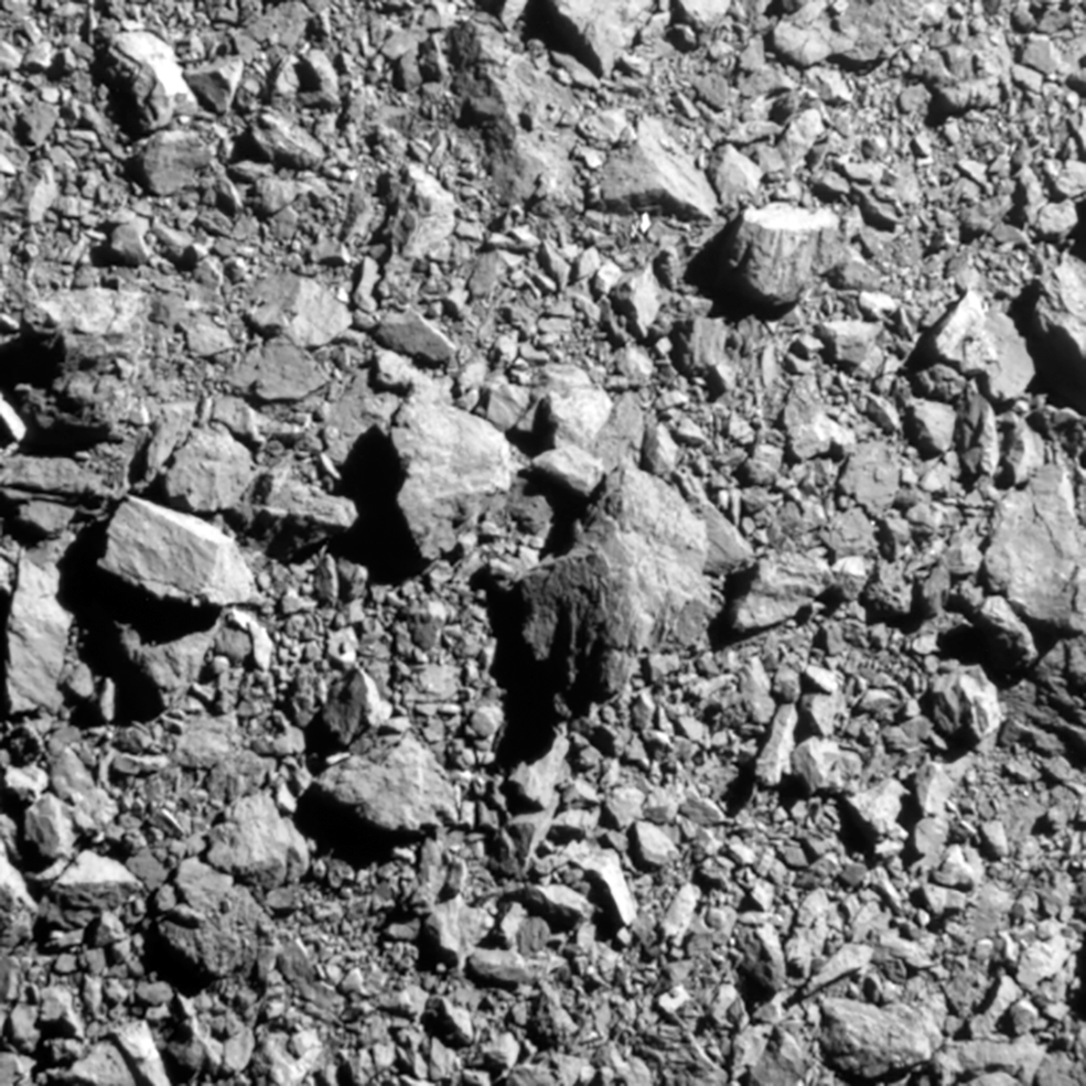 A grey rocky surface with rocks of different sizes visible. A close up image of the Dimorphos asteroid.