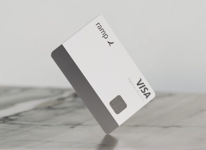 A grey Visa card with the Ramp logo on it, on a grey table surface.