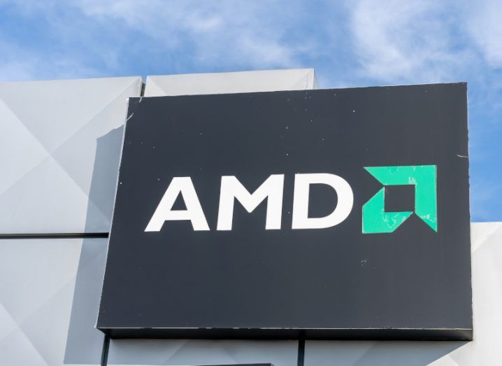 The AMD logo on a black square on a building, with a blue sky visible above.