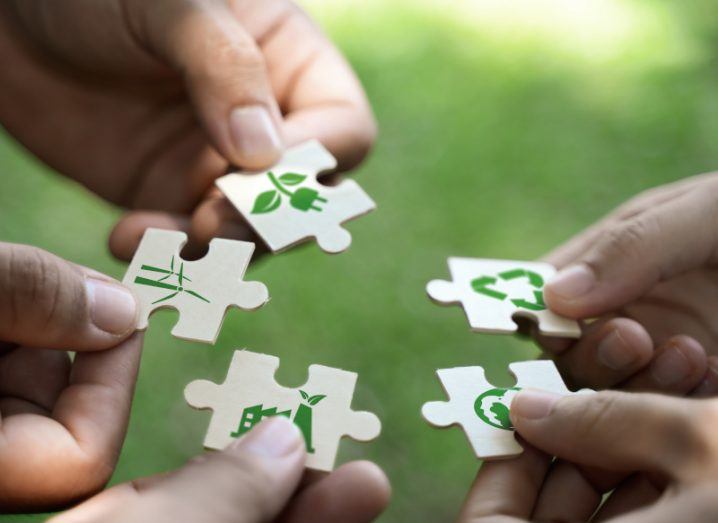 Multiple hands holding puzzle pieces that contain images linked to climate change and the circular economy.