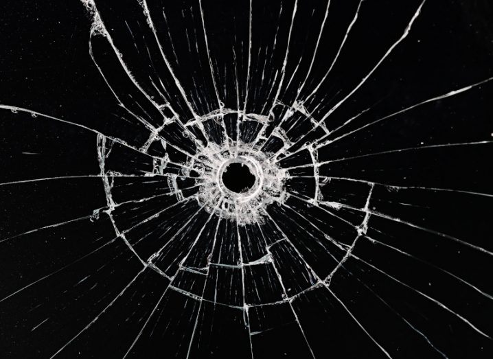 Illustration of a bullet hole on black glass, with cracks appearing out from the hole.