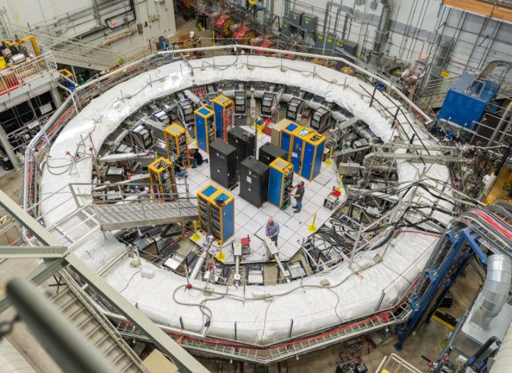 The large storage ring in the Fermilab used to test the Muon particles. People and other electrical and lab equipment are visible in the image.